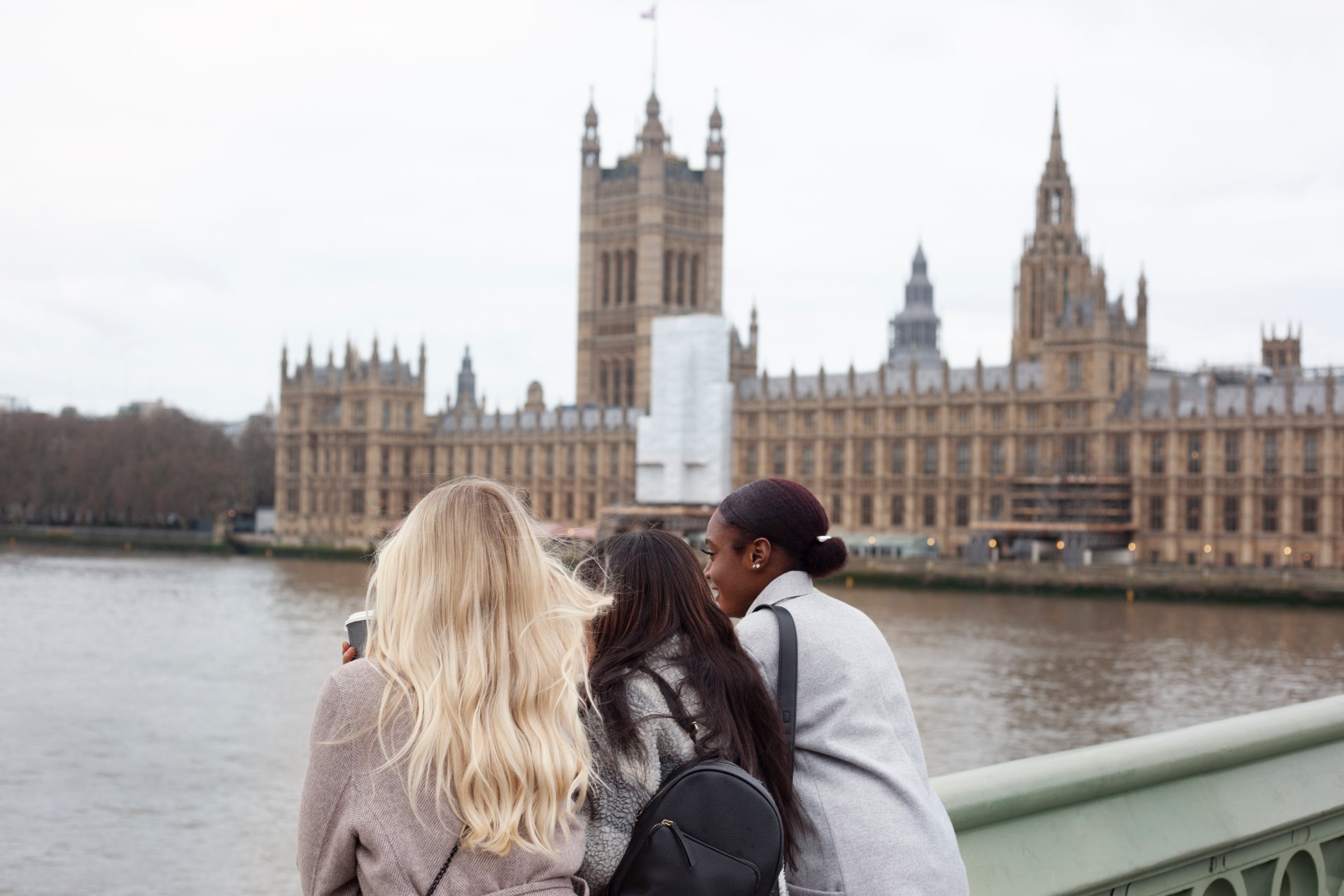 Trois jeunes femmes au bord de la Tamise à Londres, avec le palais de Westminster en arrière-plan